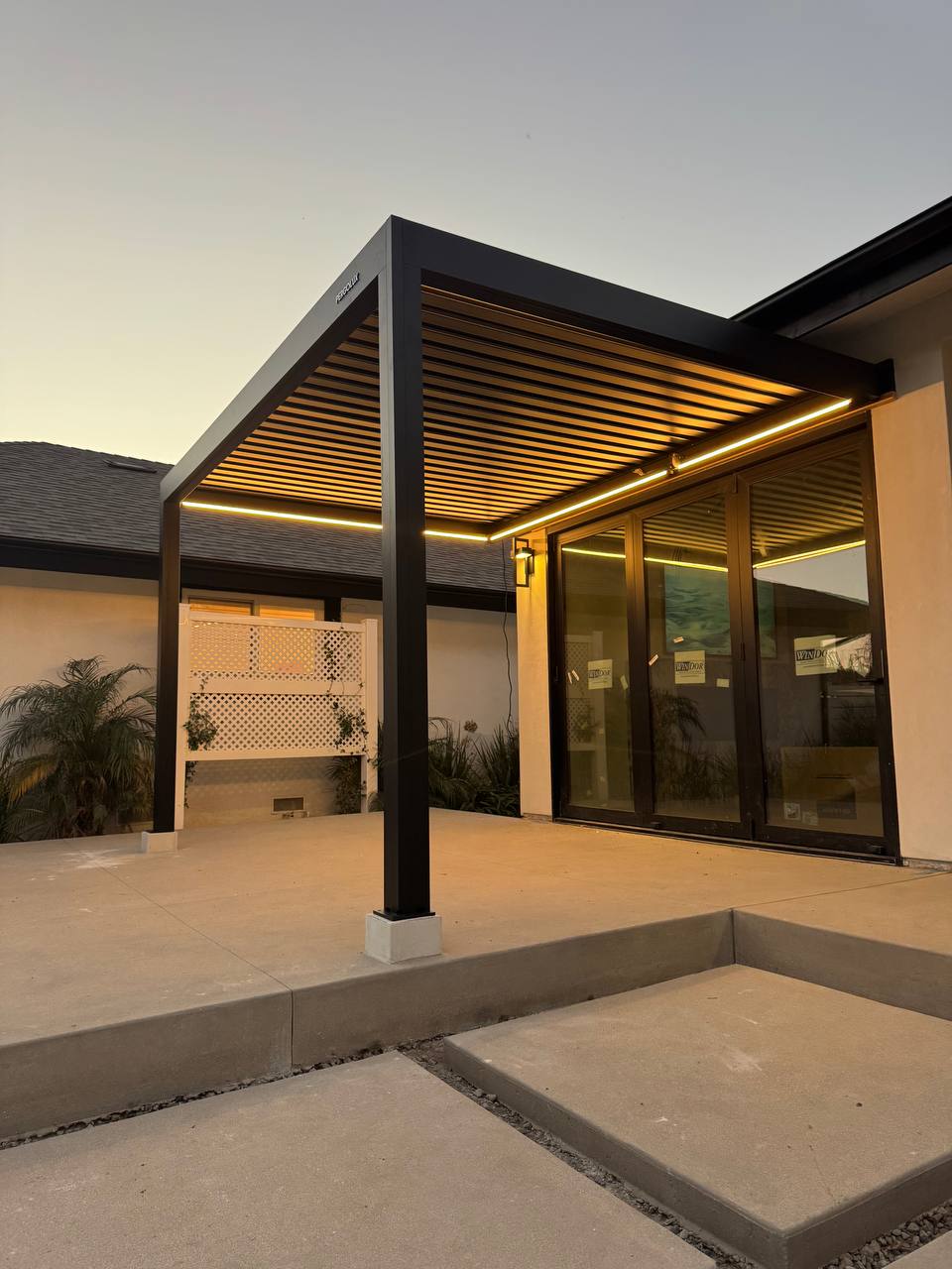 Corner view of warm pergola lighting above the concrete patio and steps.