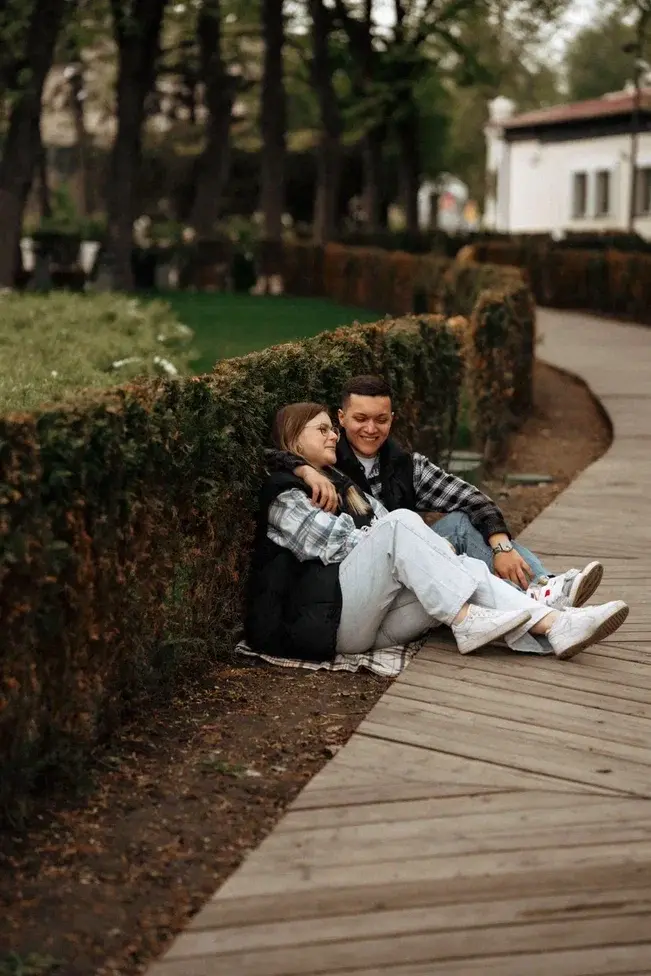 Пара сидит рядом на дорожке в парке во время прогулочной фотосессии Love Story
