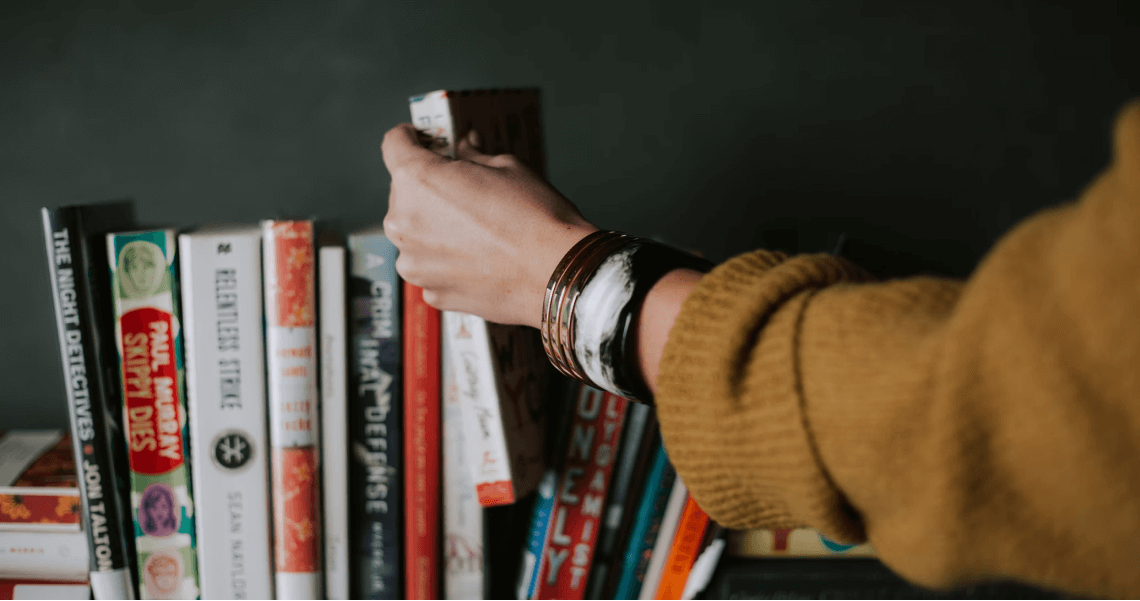 рука берет книгу с полки