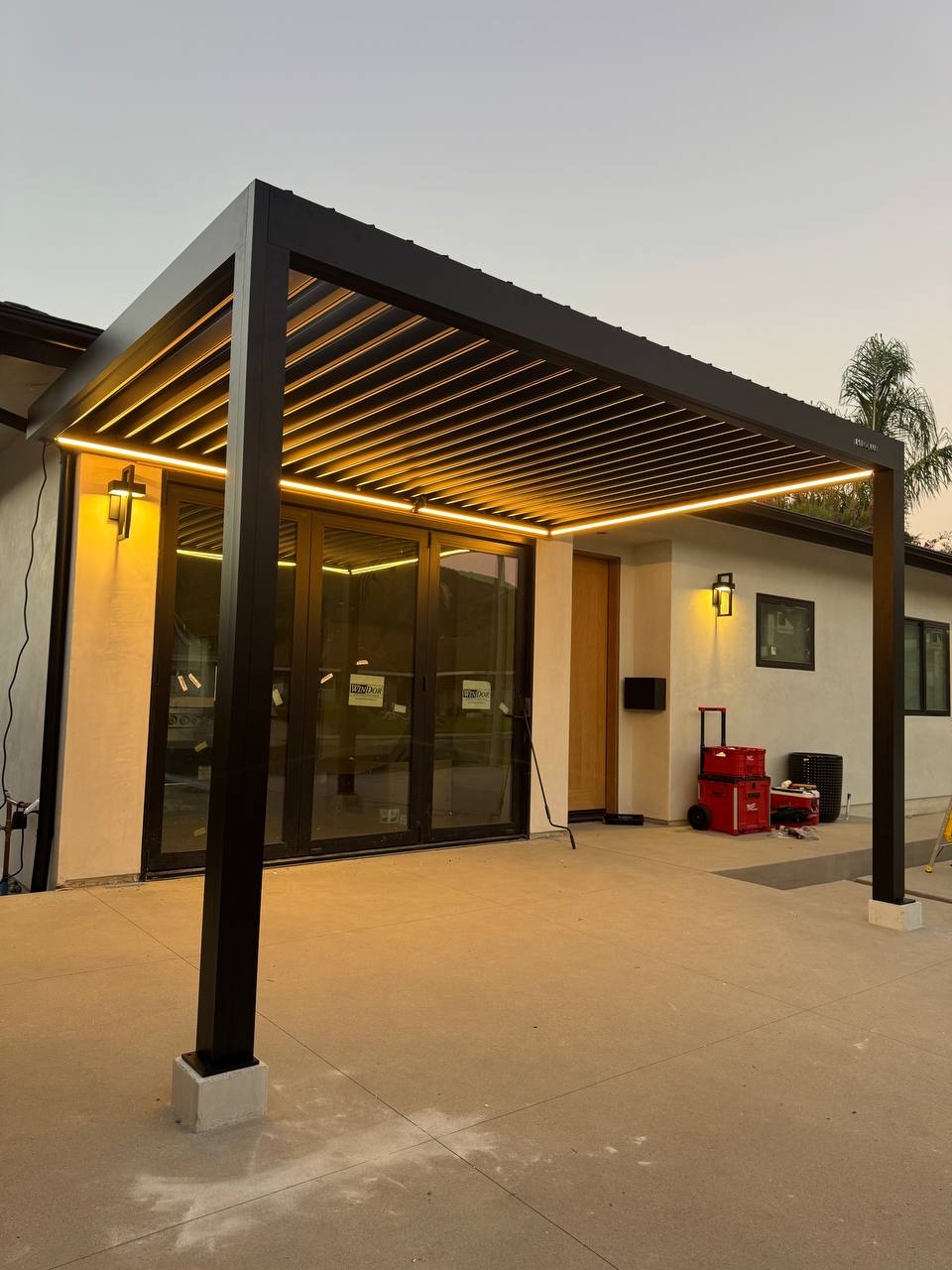 Corner view of the pergola louvers, support post and warm LED lighting at dusk.