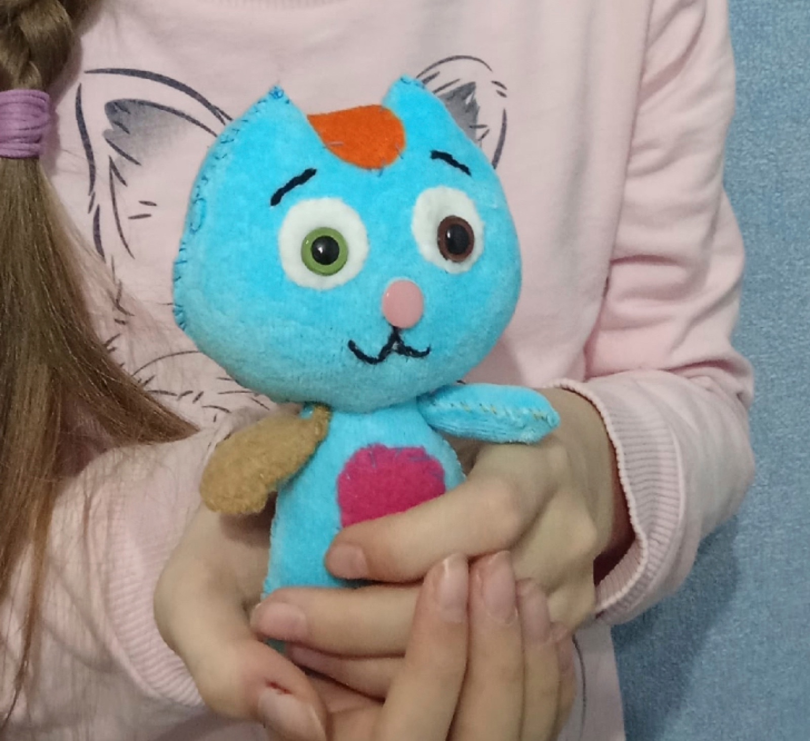 A child holding a handmade Mormitten toy