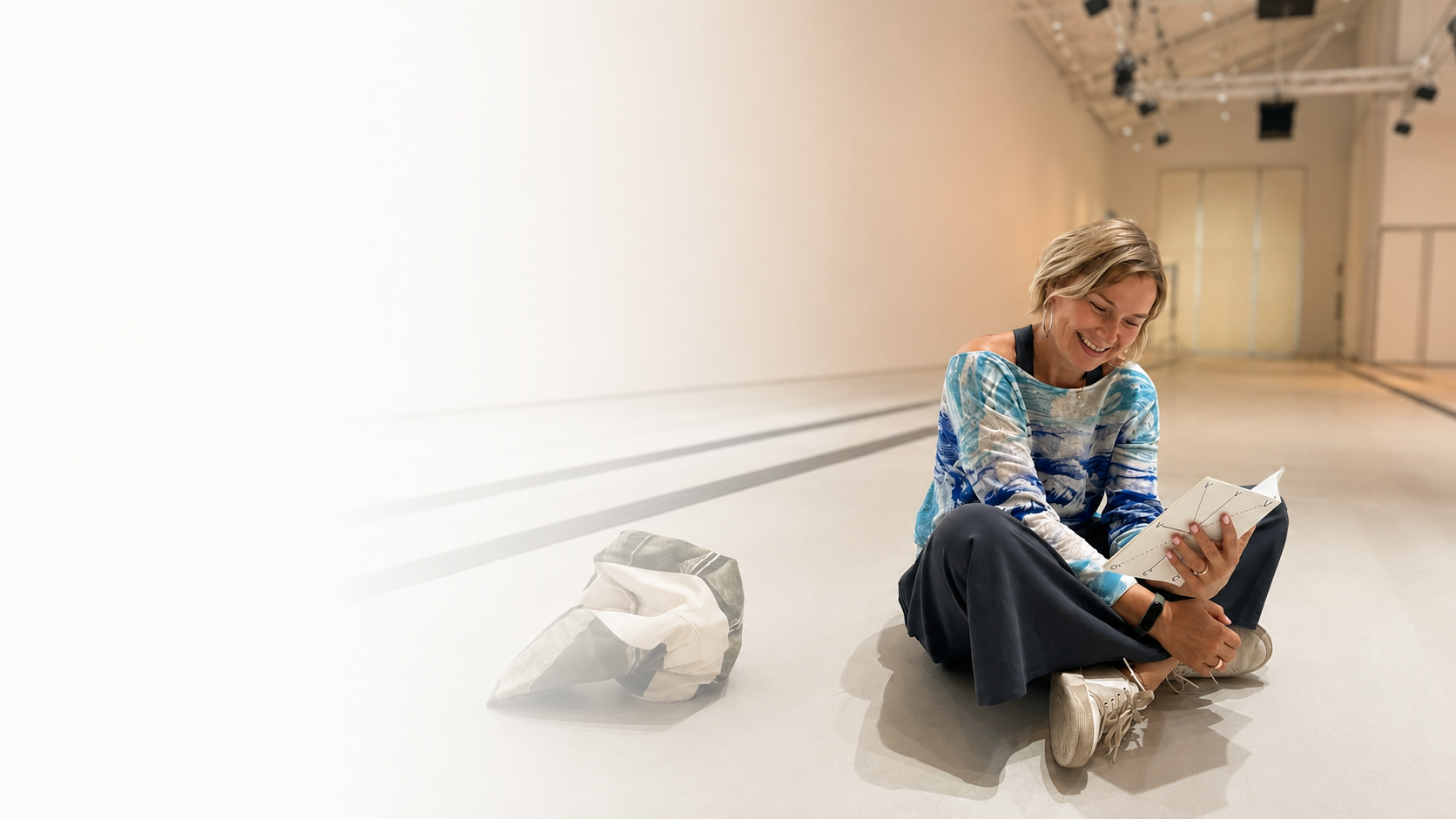 Irina Kuznetsova, designer and exhibition maker, sitting on a gallery floor reading a notebook.