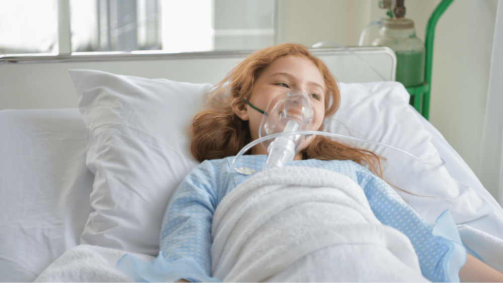 Женщина в кислородной маске лежит на больничной койке