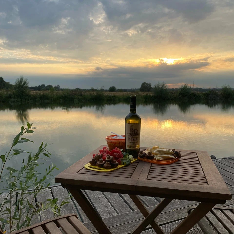 A table with wine and plates set on the deck at sunset at Ostrov Glamping