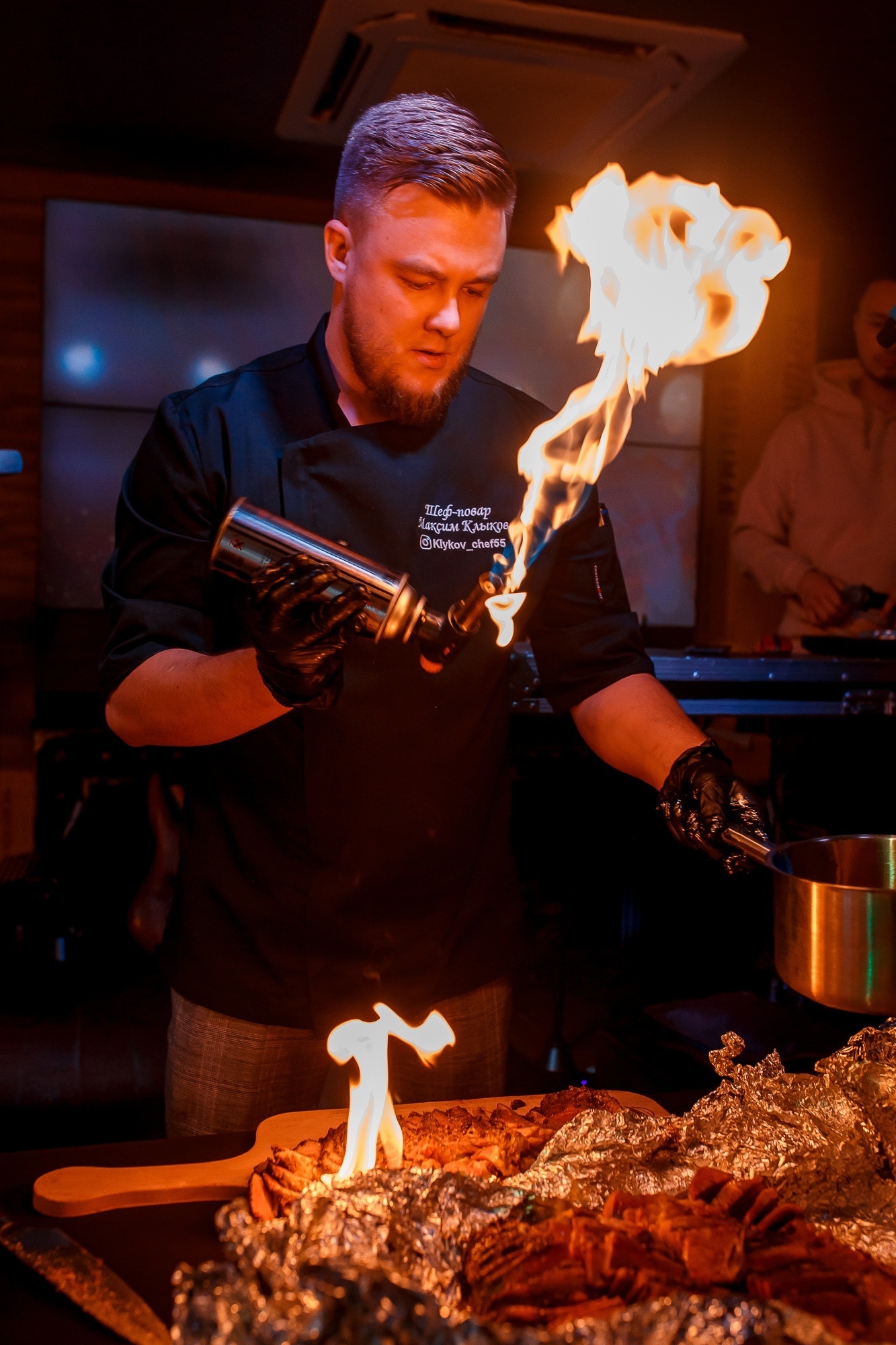 Повар Birliman Grill готовит блюдо у открытого огня