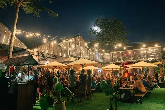 A lively outdoor crowd gathering under warm string lights at The Bench Brewery Uluwatu, a casual community hangout and one of the best bars in Bali for craft beer.