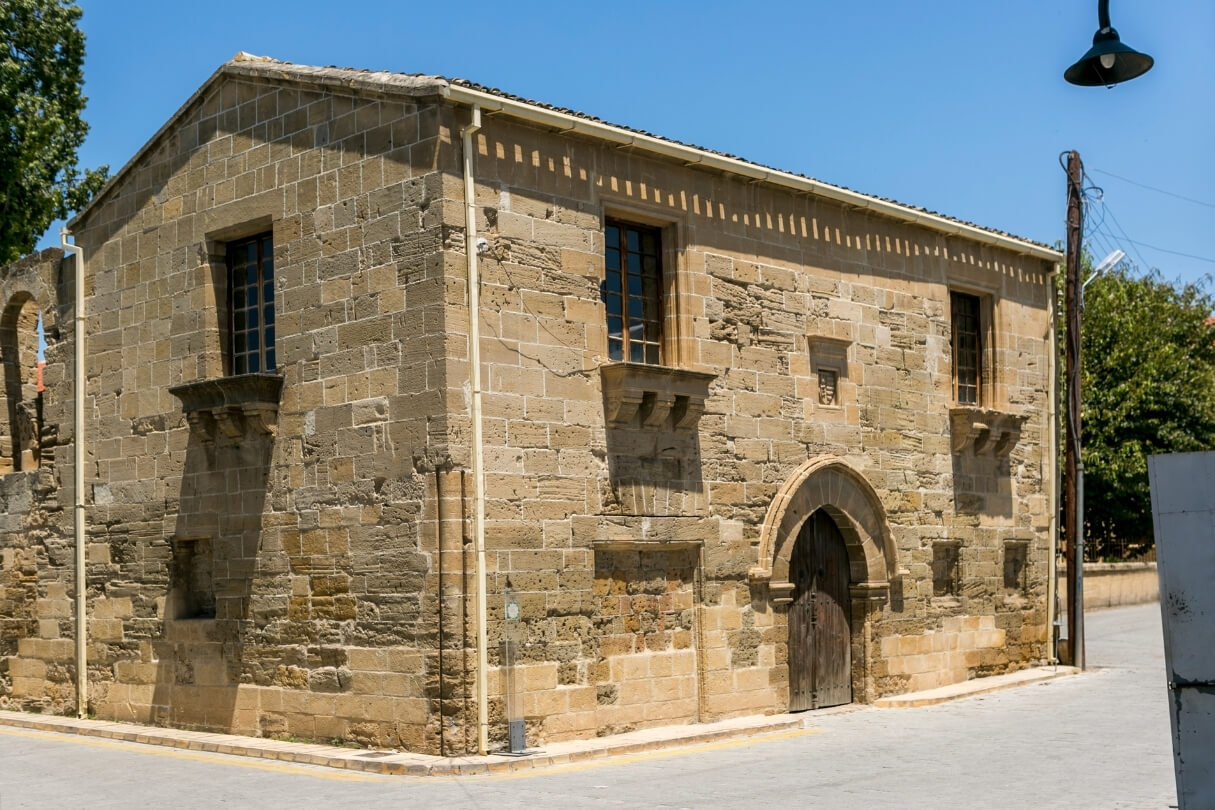 Средневековое каменное здание с арочным входом и деревянной дверью.