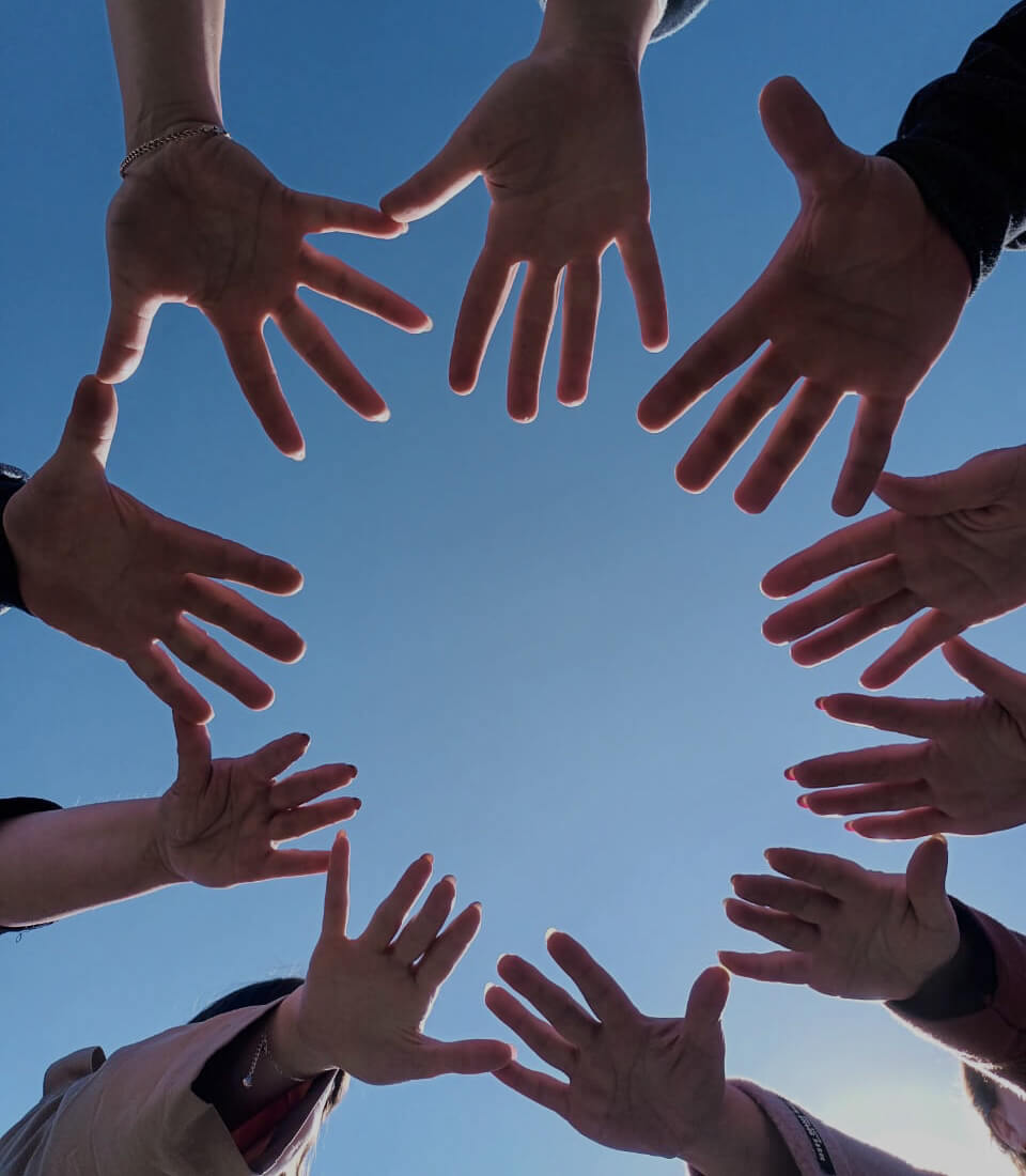 ладони нескольких людей образуют круг на фоне голубого неба, добро