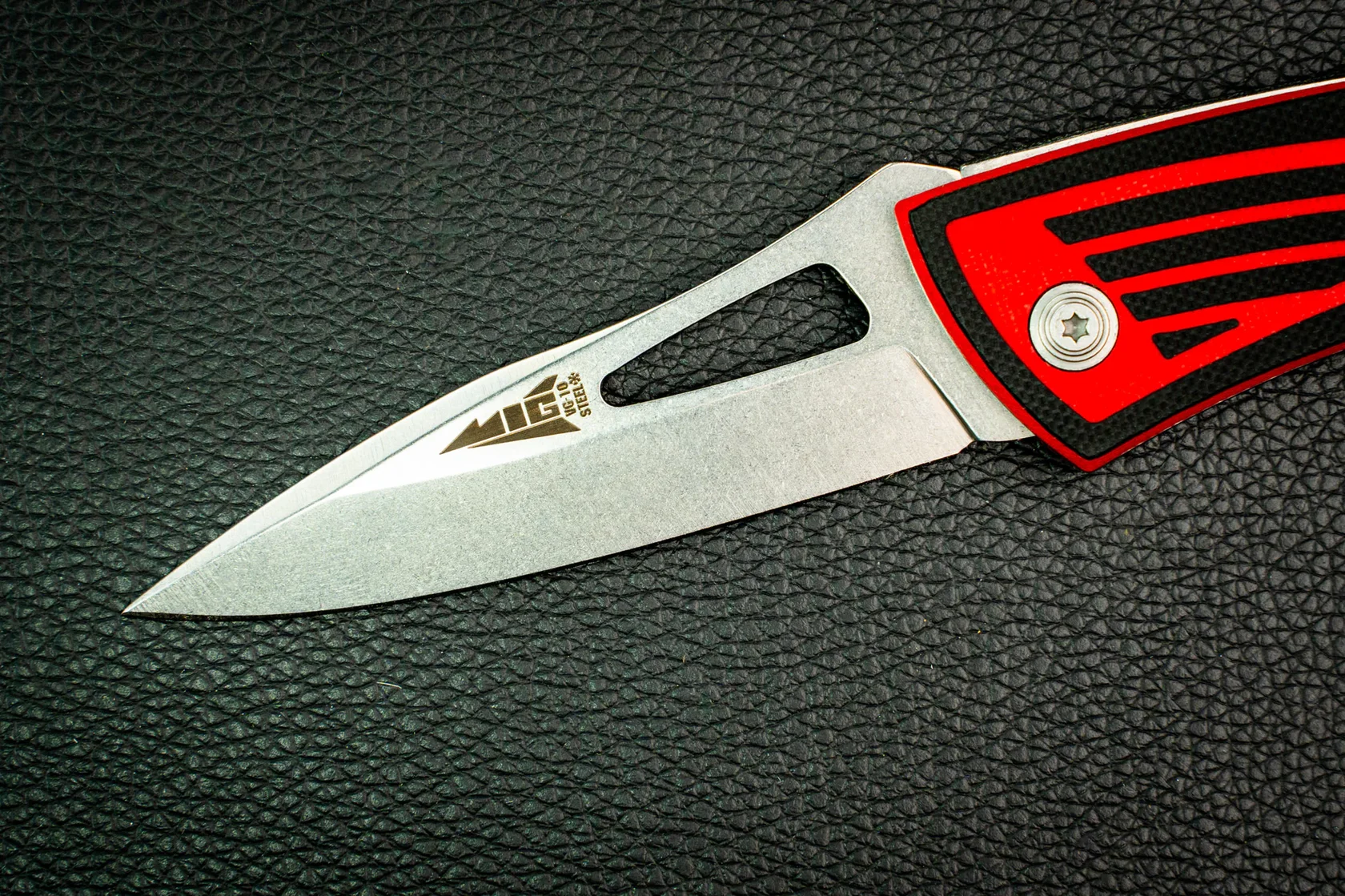 Close view of the MiG blade, pivot and layered red-and-black G10 handle