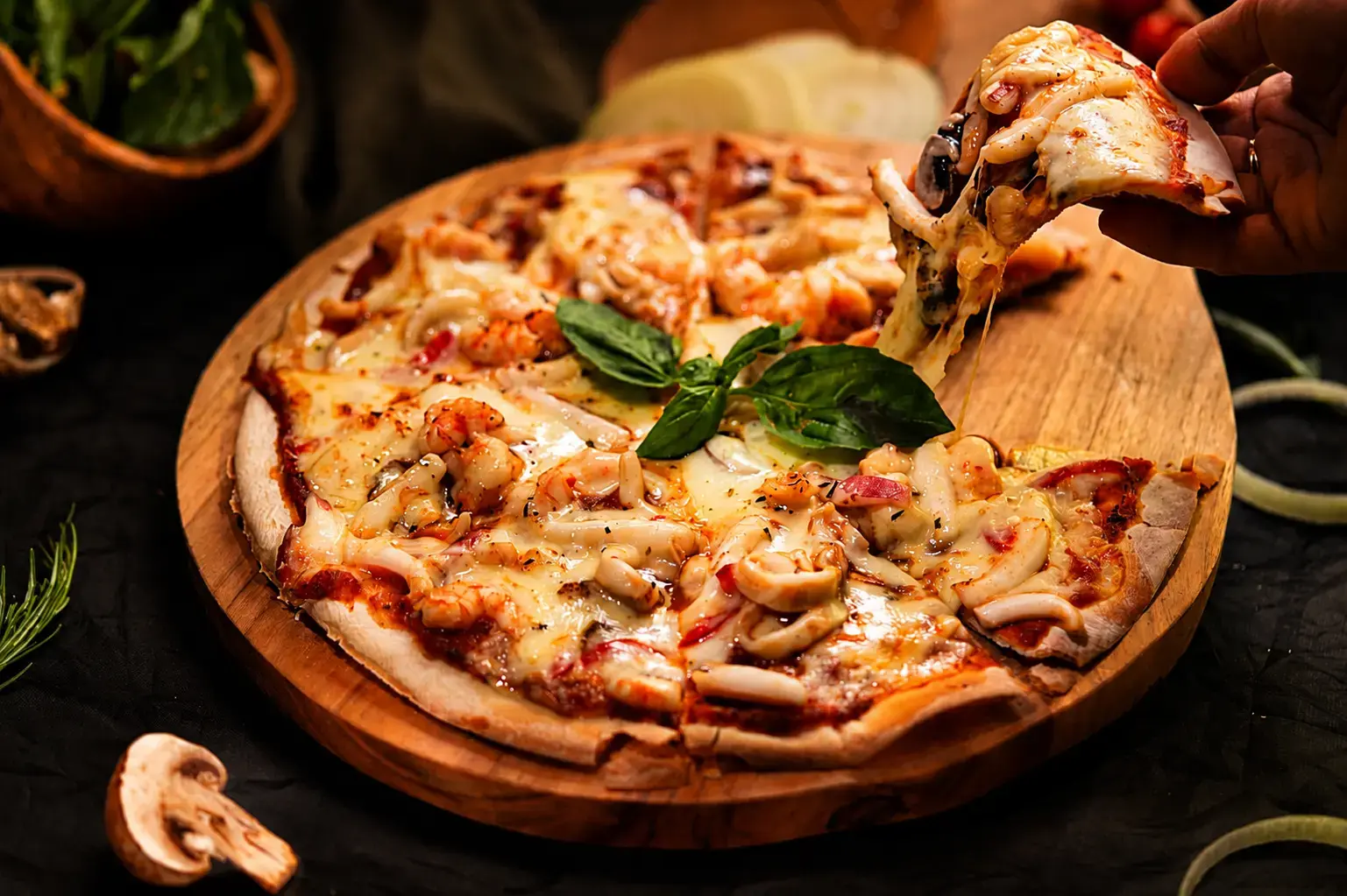 Someone taking a slice of warm cheesy seafood pizza a fantastic choice when searching for the best pizza in Ubud.