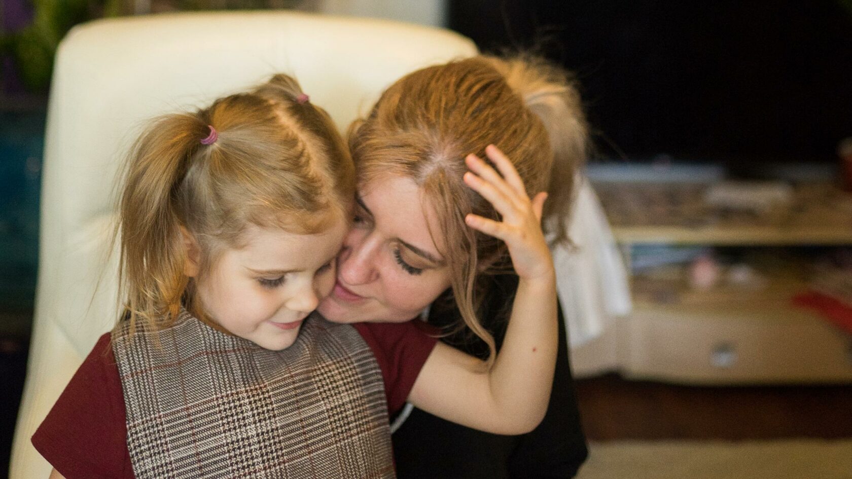 Юлия обнимает свою младшую дочку, касаясь своей щекой ее щеки. Девочка обхватывает маму рукой за голову