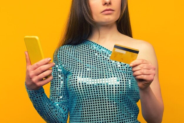 Lady buying online with a credit card and smart phone on yellow background