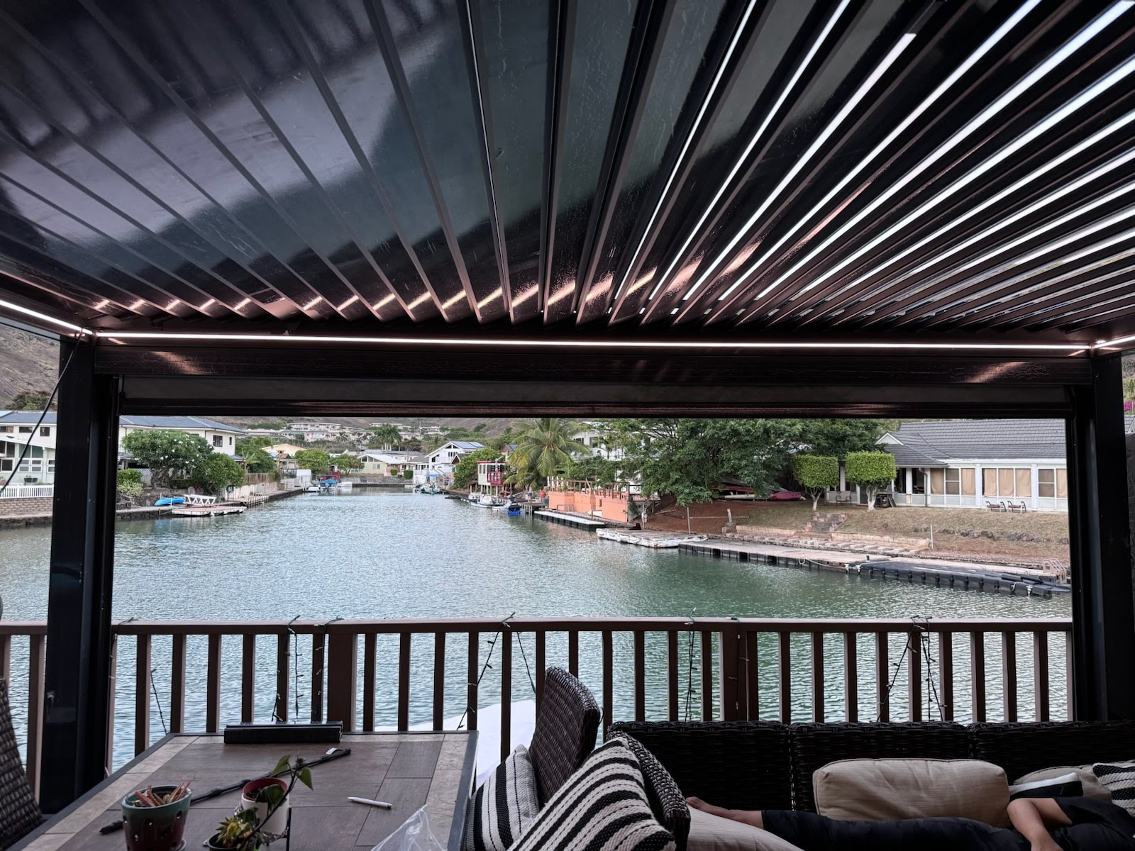 Louvered pergola with lighting overlooking a waterfront patio