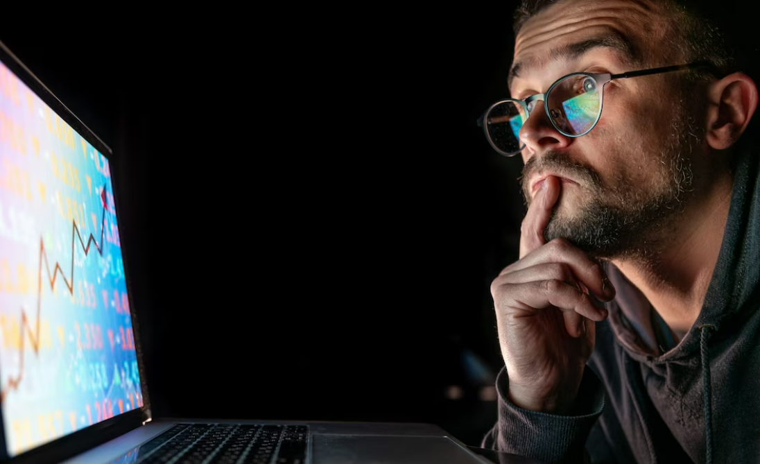 Man analyzing crypto chart patterns in front of a laptop