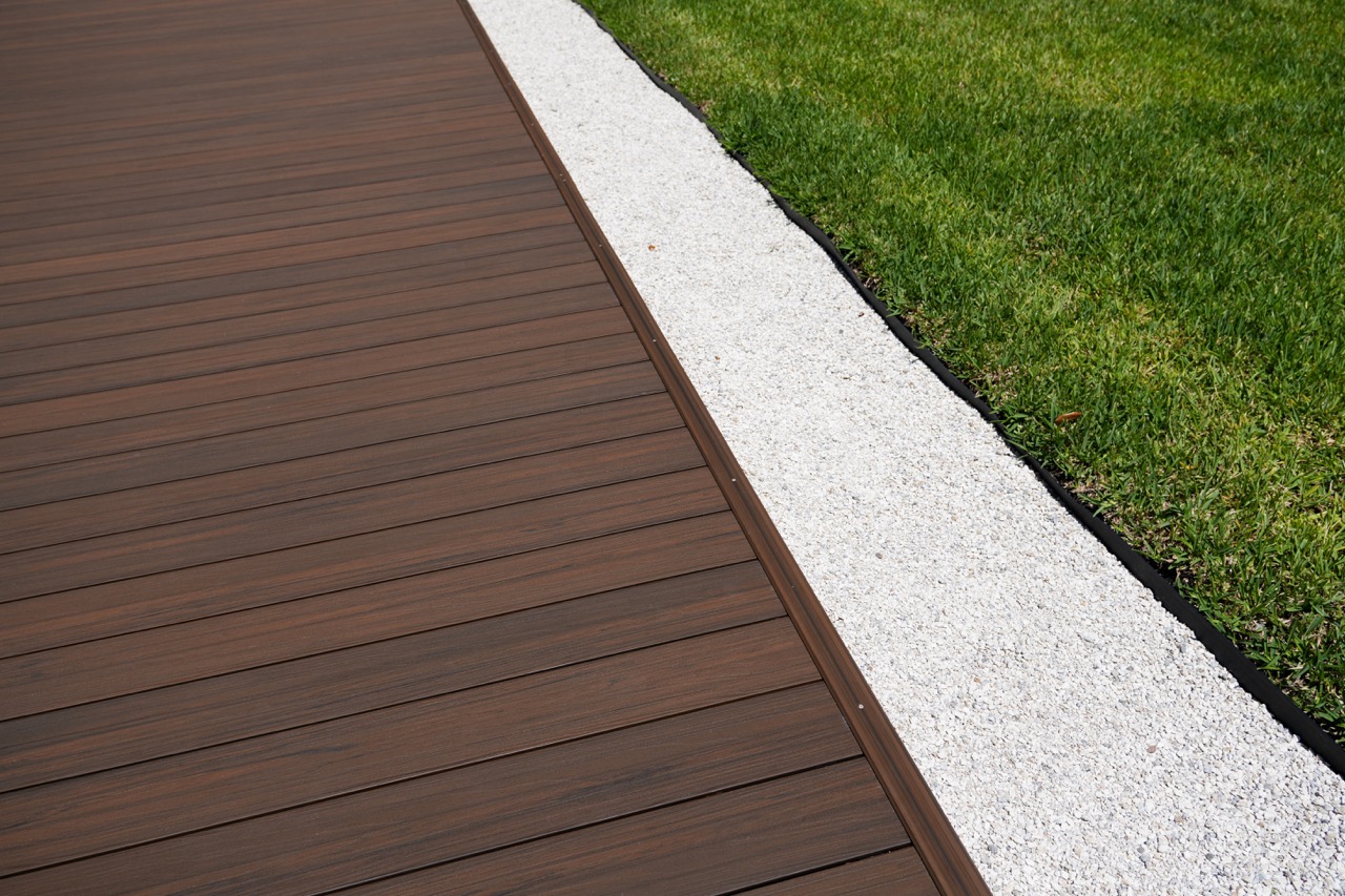 Composite decking beside lawn and white stone landscaping