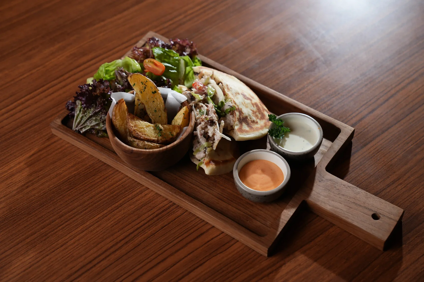 Chicken pita pocket filled with shredded chicken, lettuce, vegetables, and creamy sauce, served with potato wedges