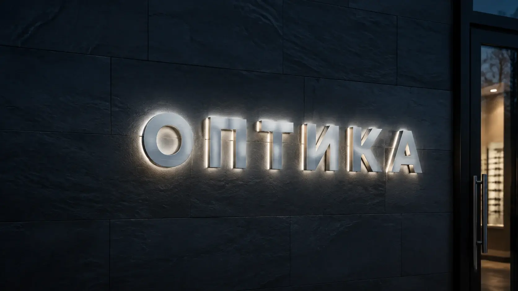 Полная надпись ОПТИКА из шлифованного серебристого металла с задней подсветкой на каменном фасаде