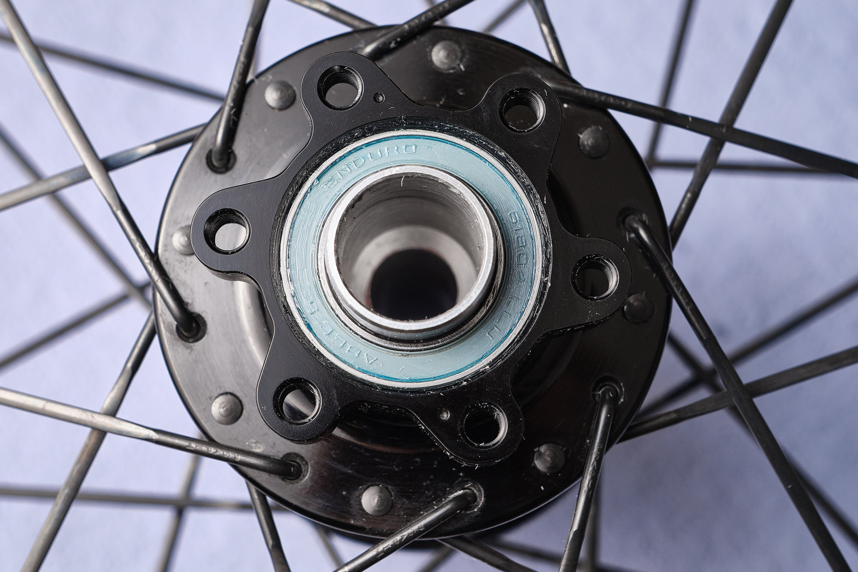 Подшипник Enduro Abec 5 с голубым пыльником в черной велосипедной втулке со спицами
