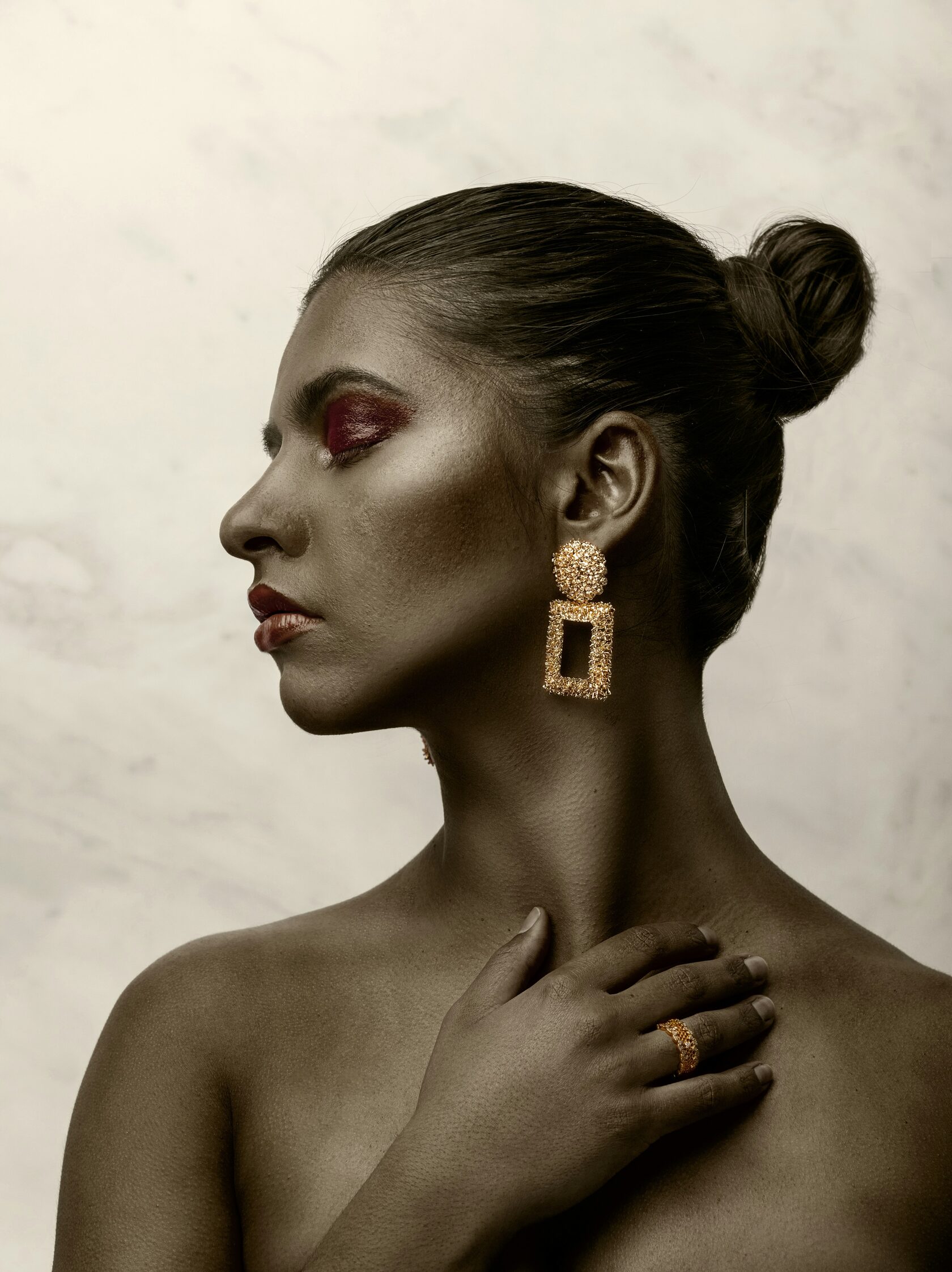 Model wearing gold-plated rectangular earrings and matching ring from Luna Dura
