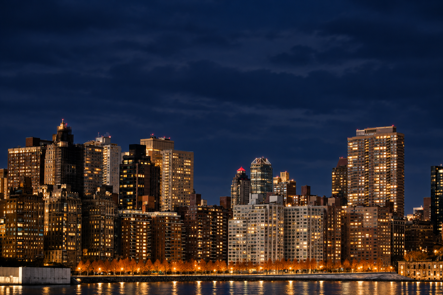 The same city skyline after dark — buildings lit against a deep night sky