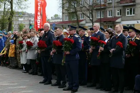 Возложение цветов к мемориалу в Псков участниками патриотической акции в честь Великой Победы, люди с красными гвоздиками у памятника героям Великой Отечественной войны