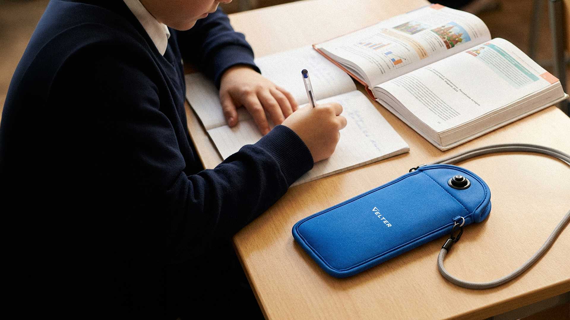 Чехол Velter с закрытым внутри смартфоном лежит на парте