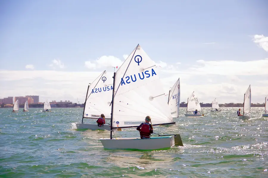 Детский швертбот Optimist под парусом на тренировке в акватории города