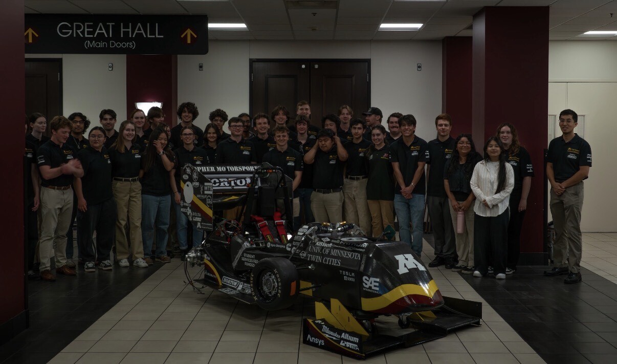 Gopher Motorsports team with their 2026 Formula SAE Electric race car at the University of Minnesota unveil event.