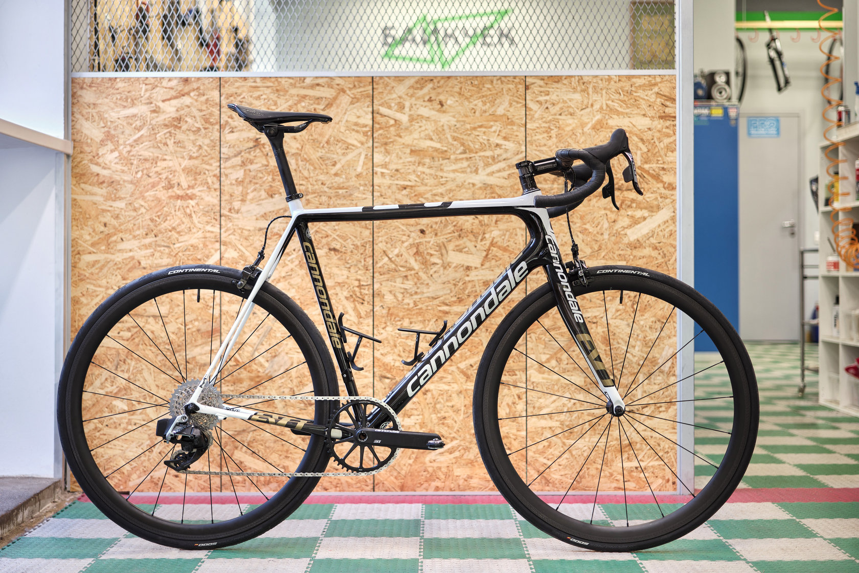 Черно-белый шоссейный велосипед Cannondale у деревянной перегородки в мастерской