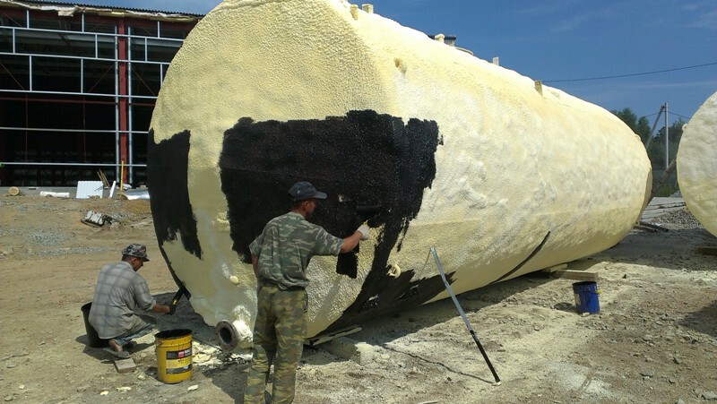 человек монтирует утеплитель на круглую емкость