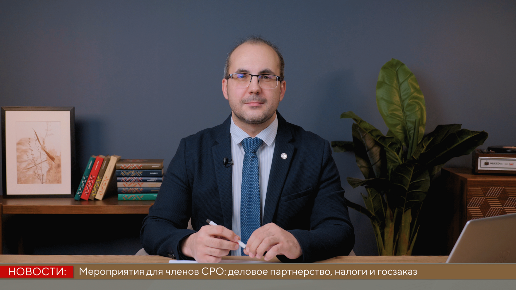 Студия ведущий за столом с ноутбуком и титрами