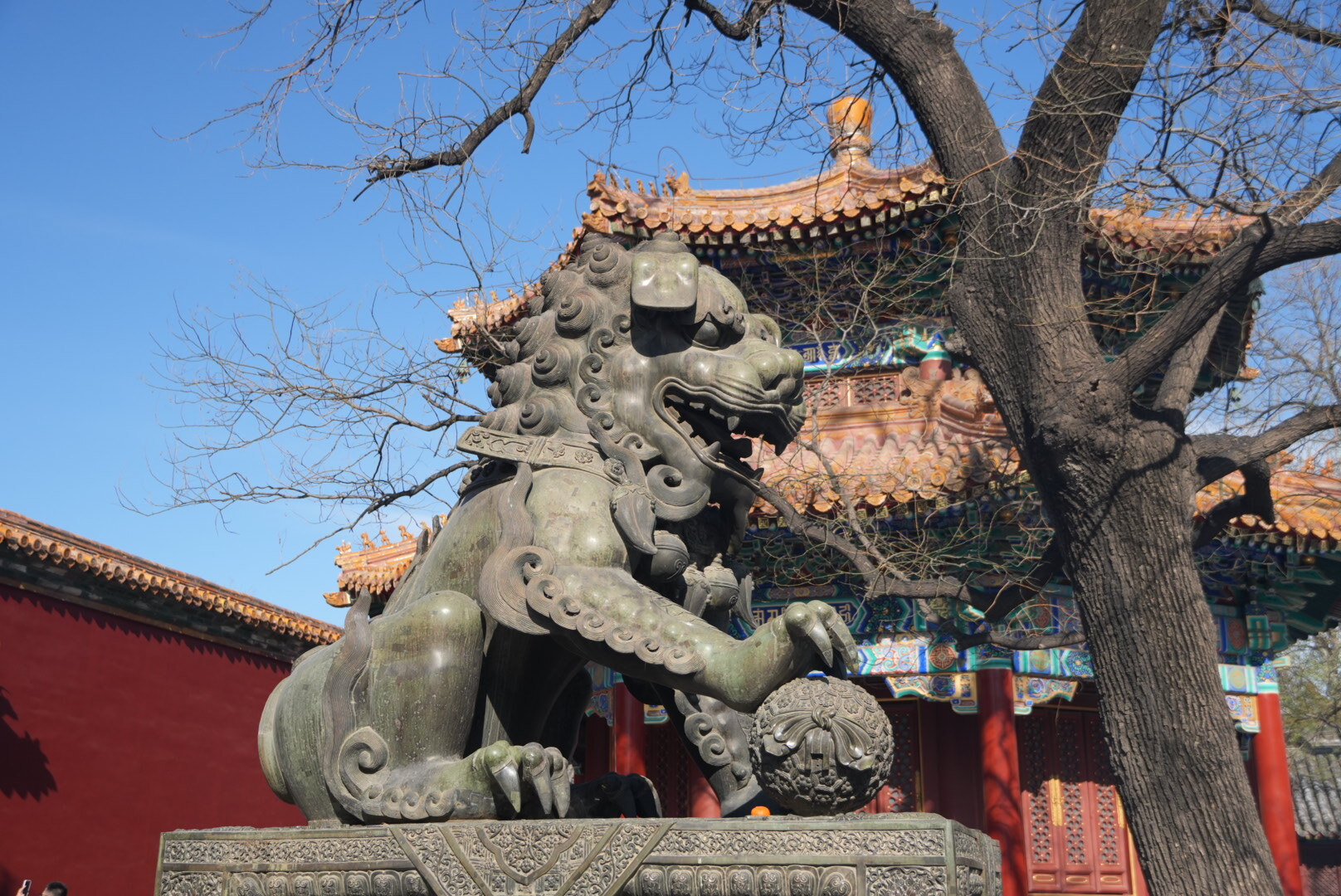 Каменная статуя китайского льва-стража с шаром у входа в храмовый комплекс в Китае