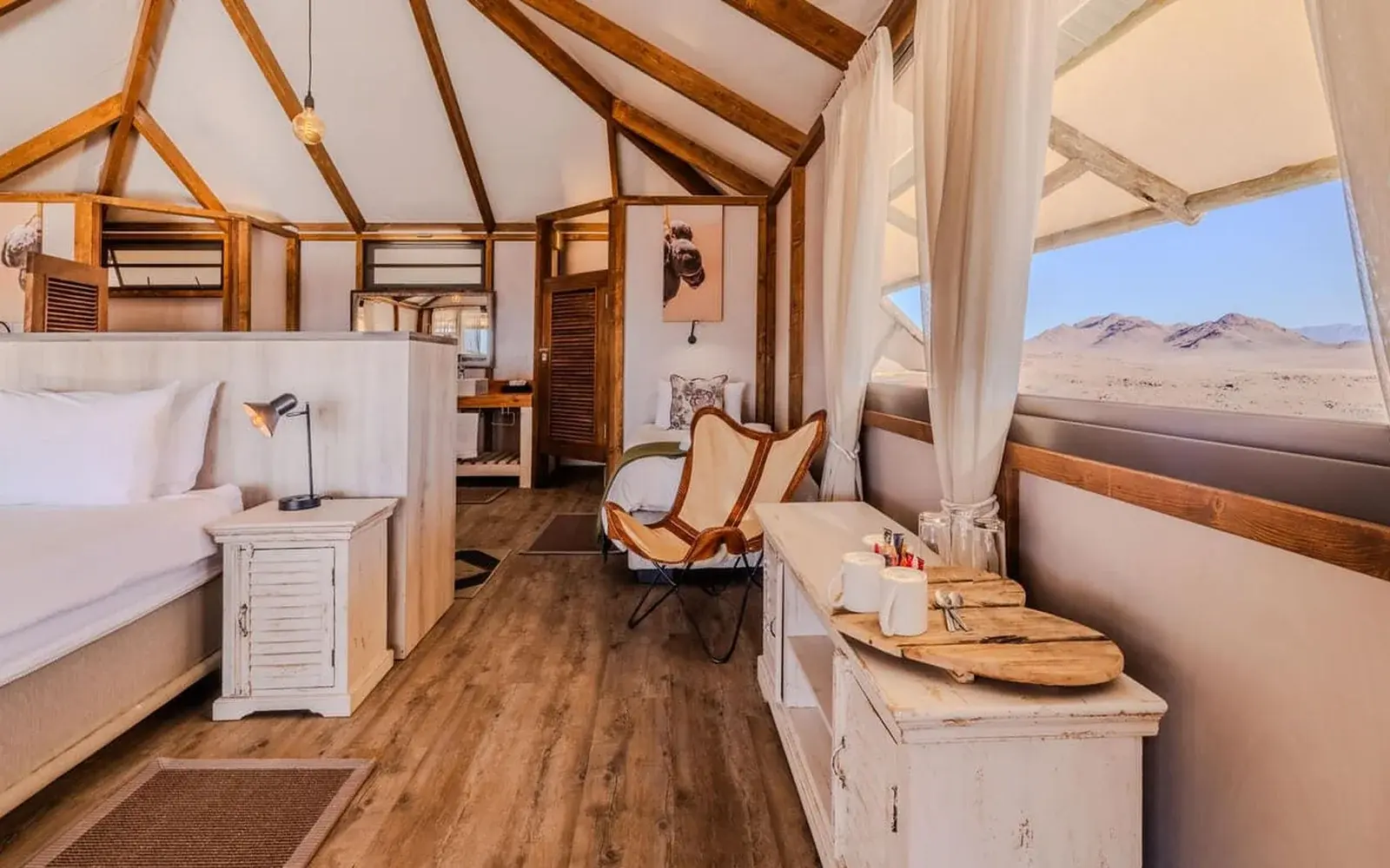 Внутри палатки: кровать, деревянный каркас и окно в пустыню, Desert Hills Glamping Camp