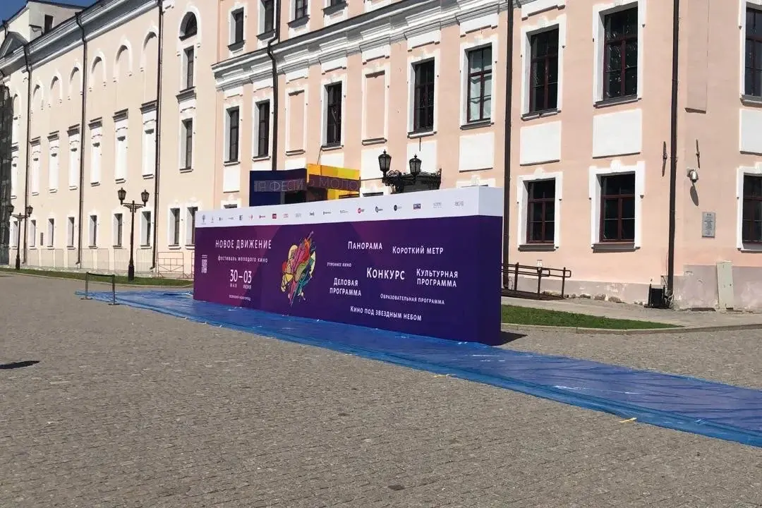 Уличный пресс-волл с фиолетовым баннером на площади перед зданием