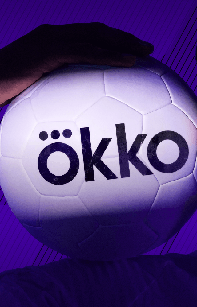 Айдентика Okko Sport: крупный портрет спортсмена на фиолетовом фоне, он держит футбольный мяч с логотипом Ökko у головы.