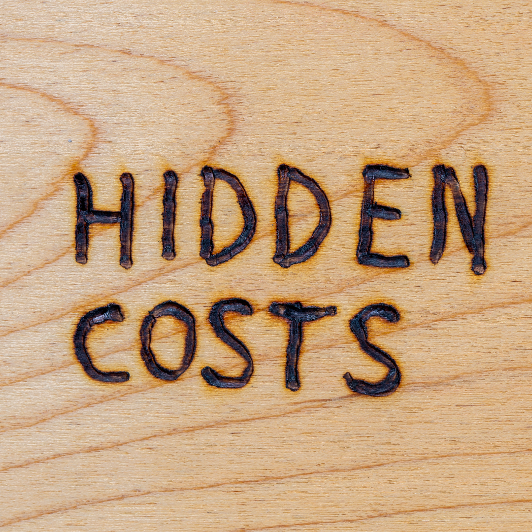 the word hidden costs written on a wooden surface