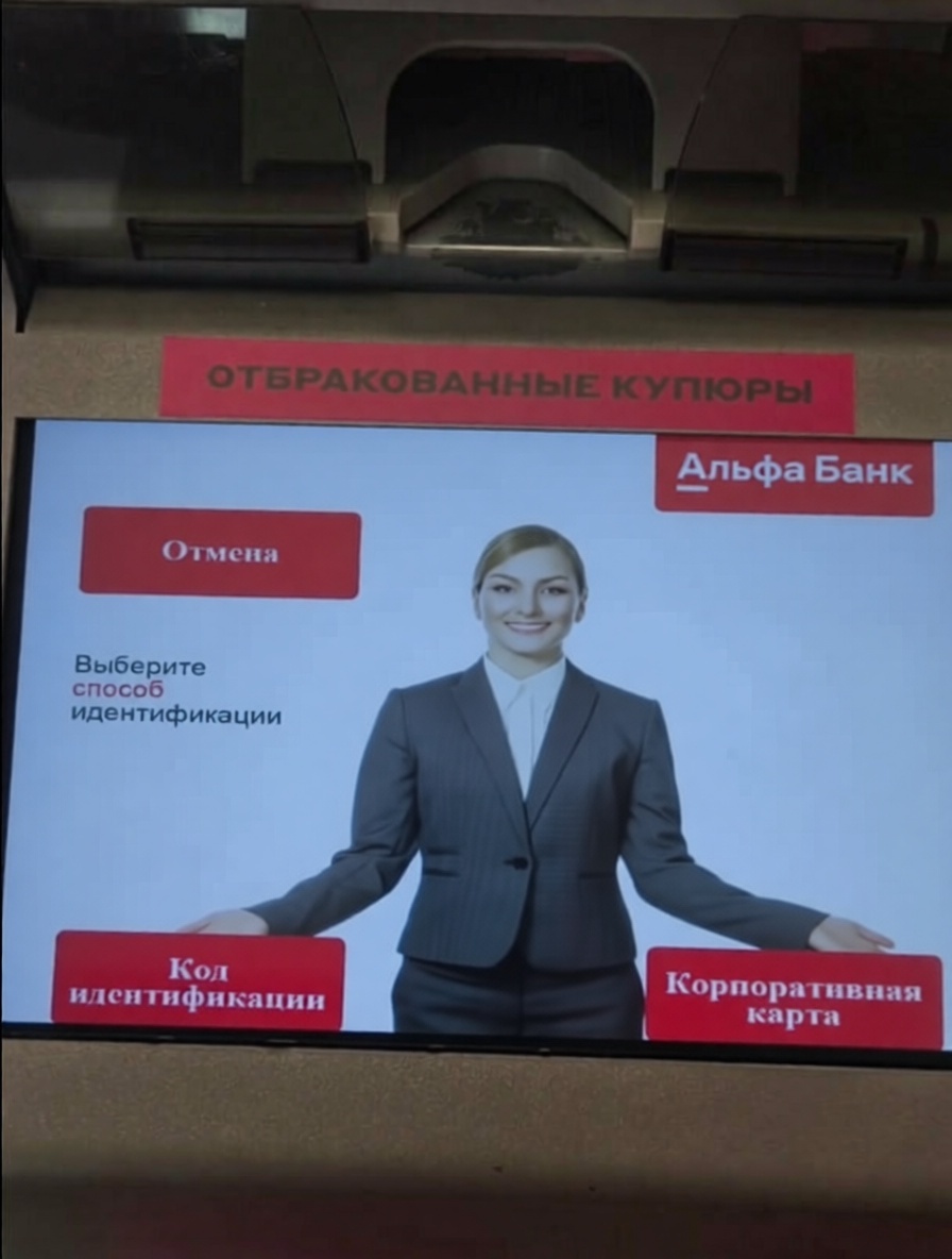 На экране банкомата Альфа Банк отображается изображение женщины в костюме. Есть кнопки «Отмена», «Код идентификации» и «Корпоративная карта».