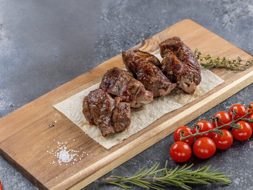 Мякоть баранины на разделочной доске с томатами и розмарином