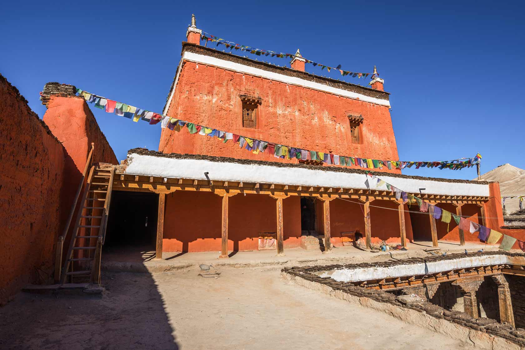 Монастырь Джампа Лакханг в Ло-Мантанге: трехэтажное здание с красными глинобитными стенами и молитвенными флагами