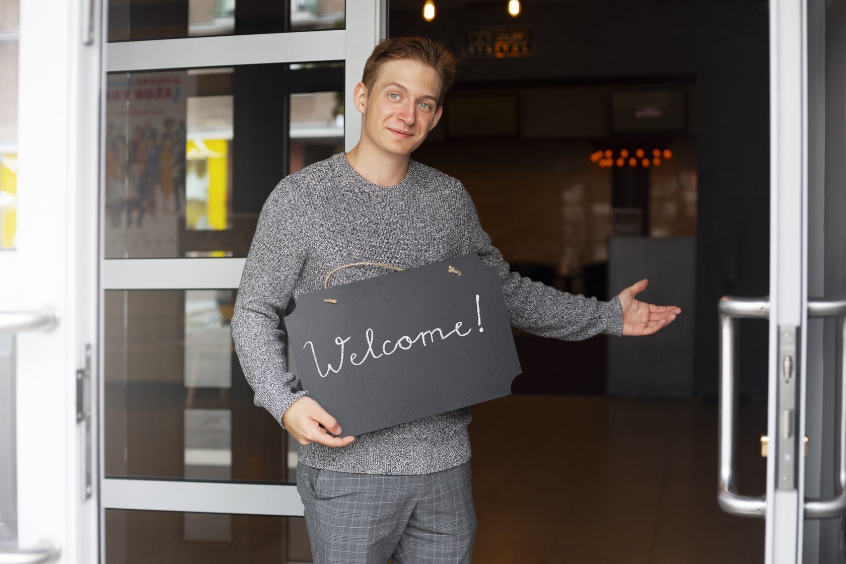 мужчина с табличкой Добро пожаловать