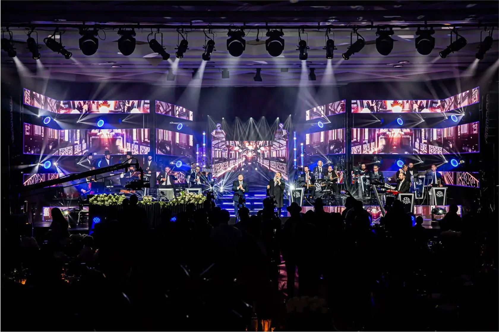 This may contain: the stage is set up for an event with blue curtains and lights on it, along with chairs