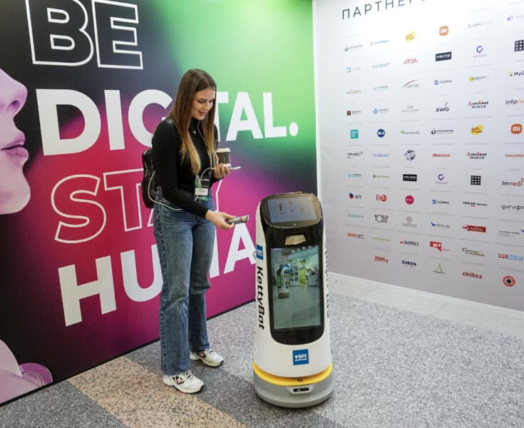 Сервисный робот KettyBot приветствует гостей у стойки регистрации отеля