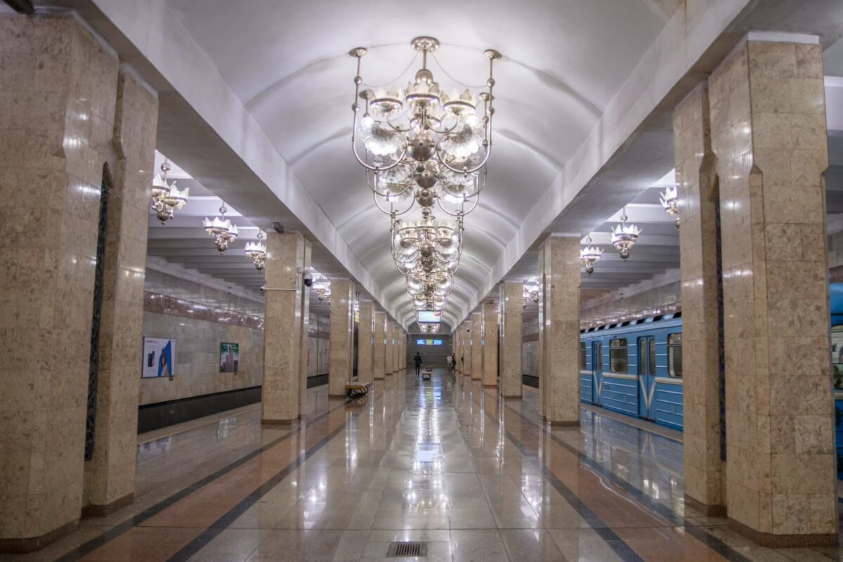 Ornate and elegant interior of a Tashkent metro station showing detailed ceiling patterns and polished floors with trains on each side