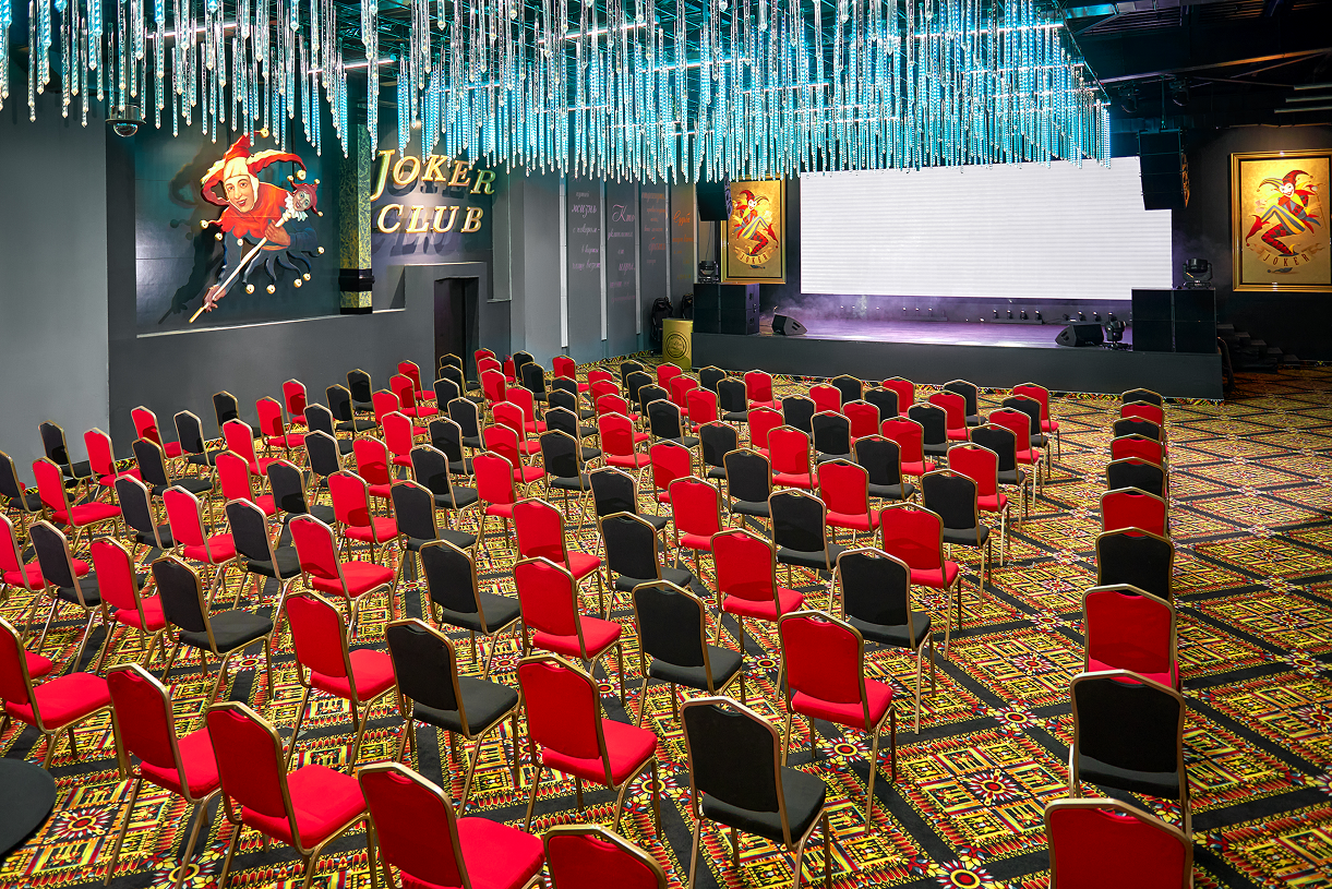 Зал со сценой и рядами кресел, подготовленный к мероприятию, на курорте «Сибирская Монета»