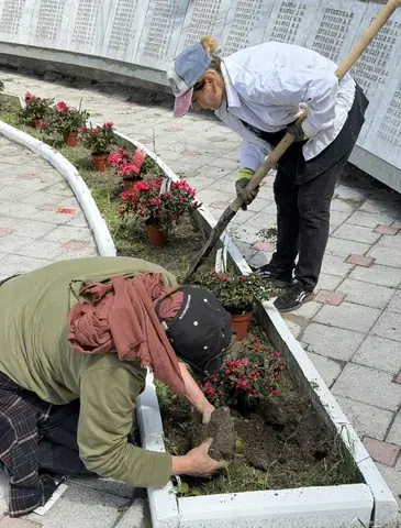 Специалисты высаживают растения на территории у памятника