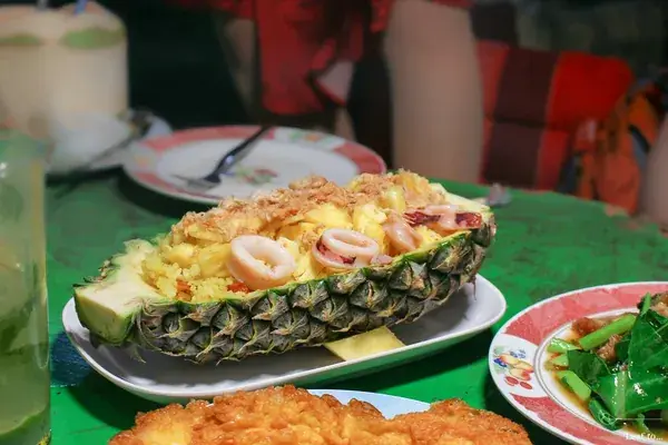 Жареный рис с морепродуктами в половинке ананаса на столе кафе