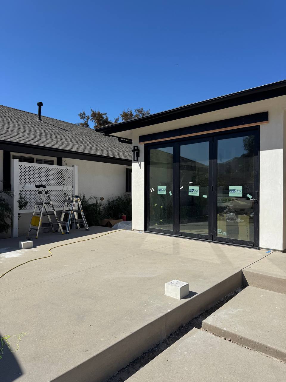 Side view of the uncovered patio with a prepared support base and ladders before installation.
