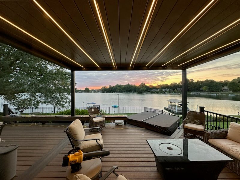 Covered pergola deck with integrated ceiling lighting at sunset