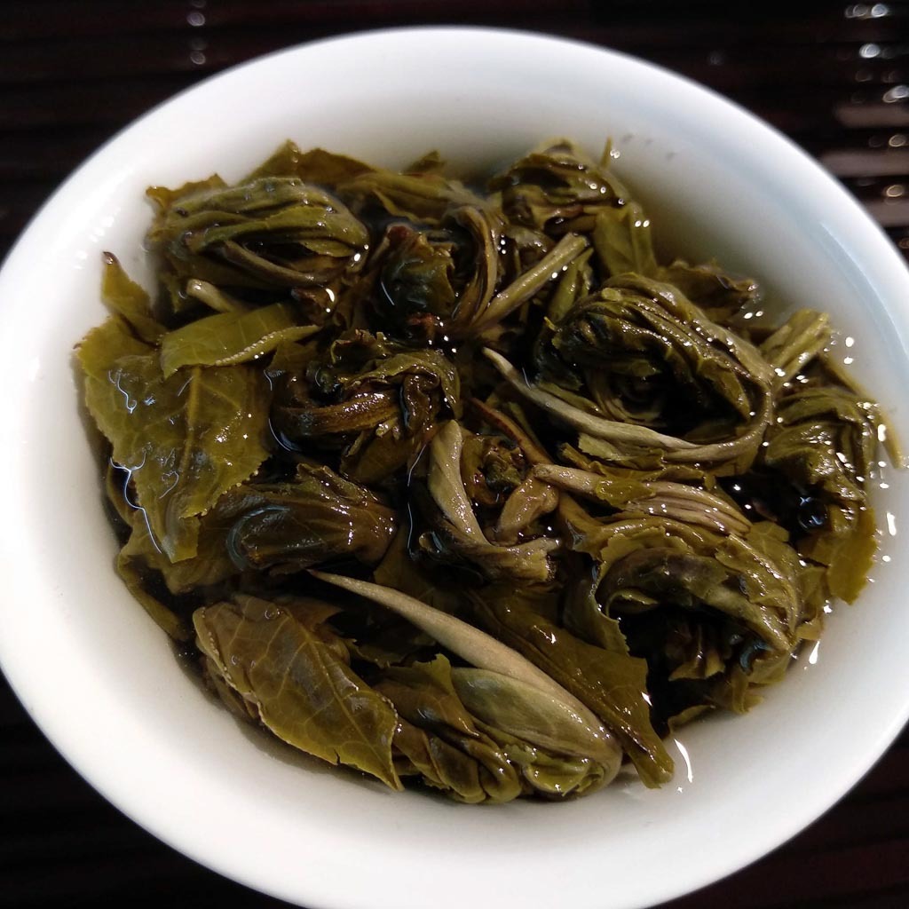 Unfurling Jasmine Phoenix Eye tea leaves in a clear glass