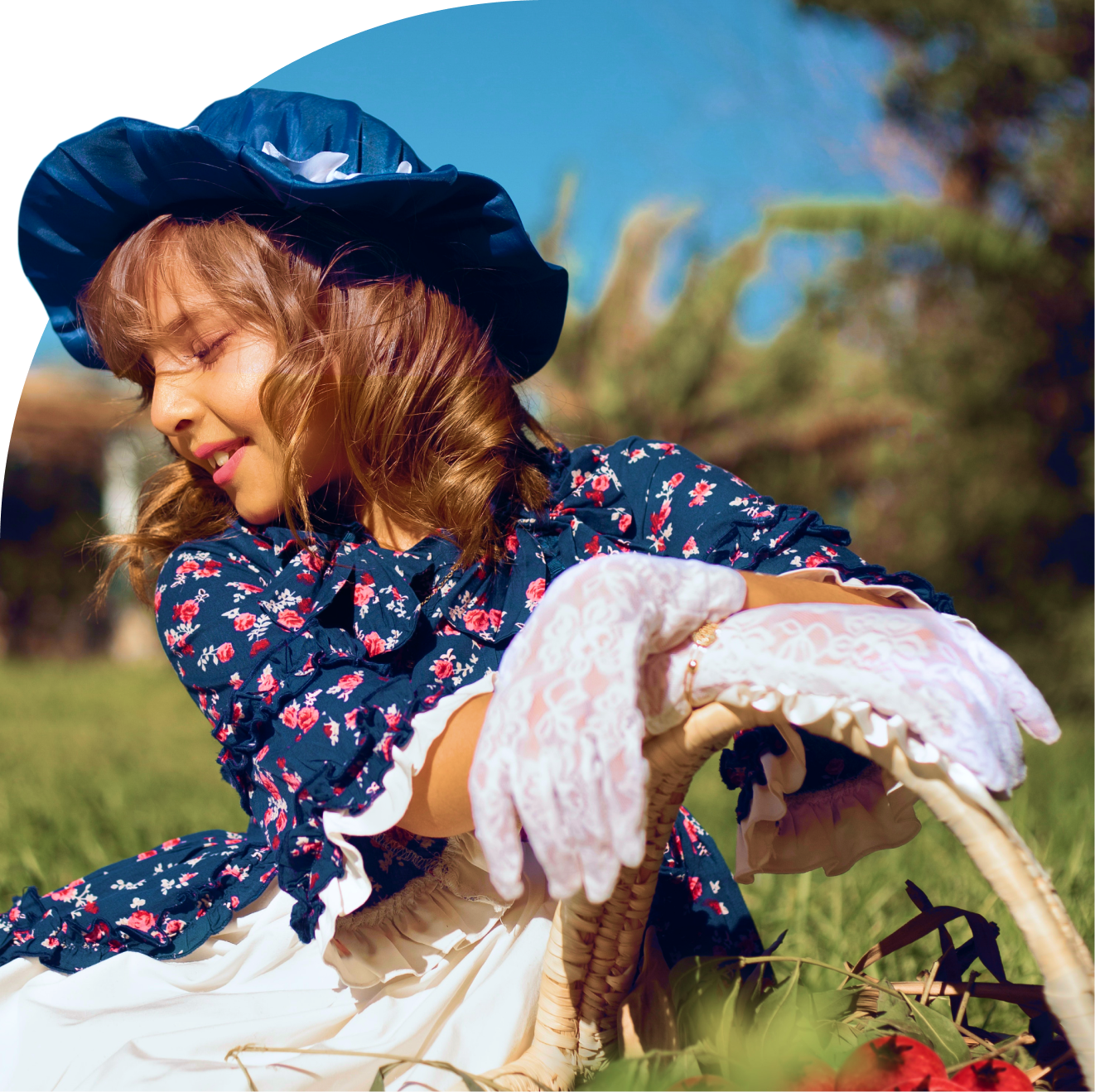 Девочка-актрисса сидит на фоне зеленого поля и держит корзинку с ягодами в руках